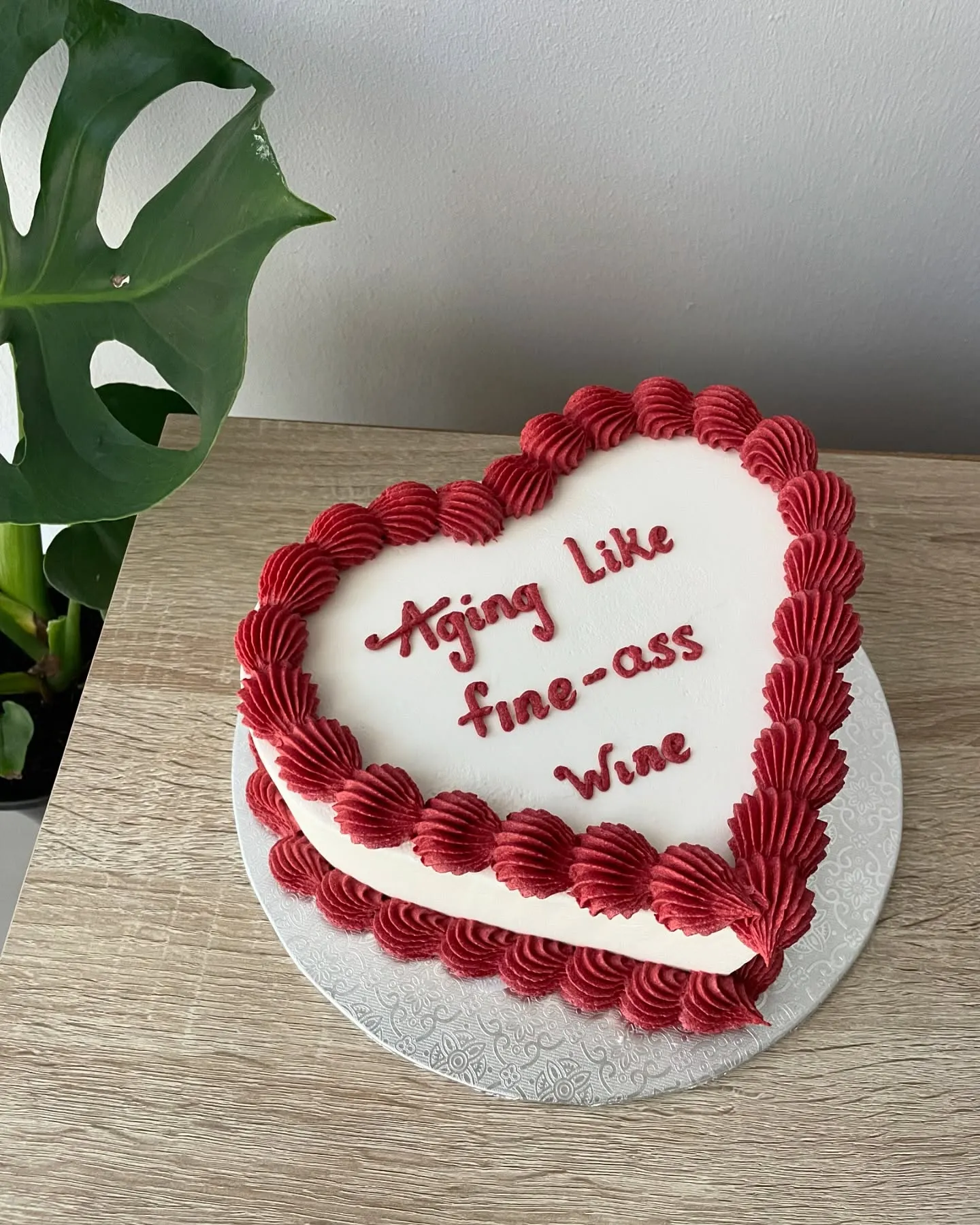 White heart cake with red shell piping and a cheeky piped birthday message