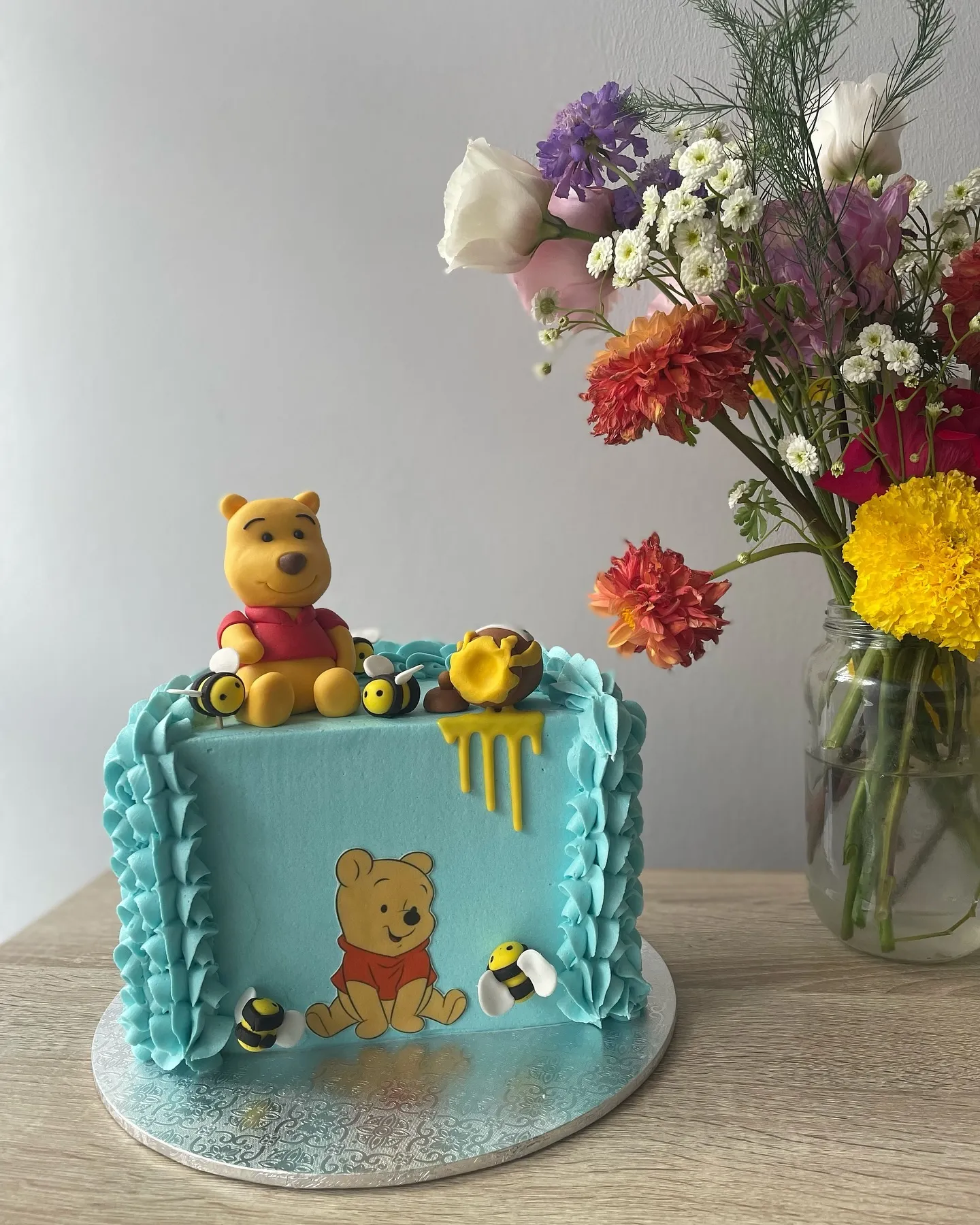 Blue ruffled Winnie the Pooh cake with a handmade Pooh figure