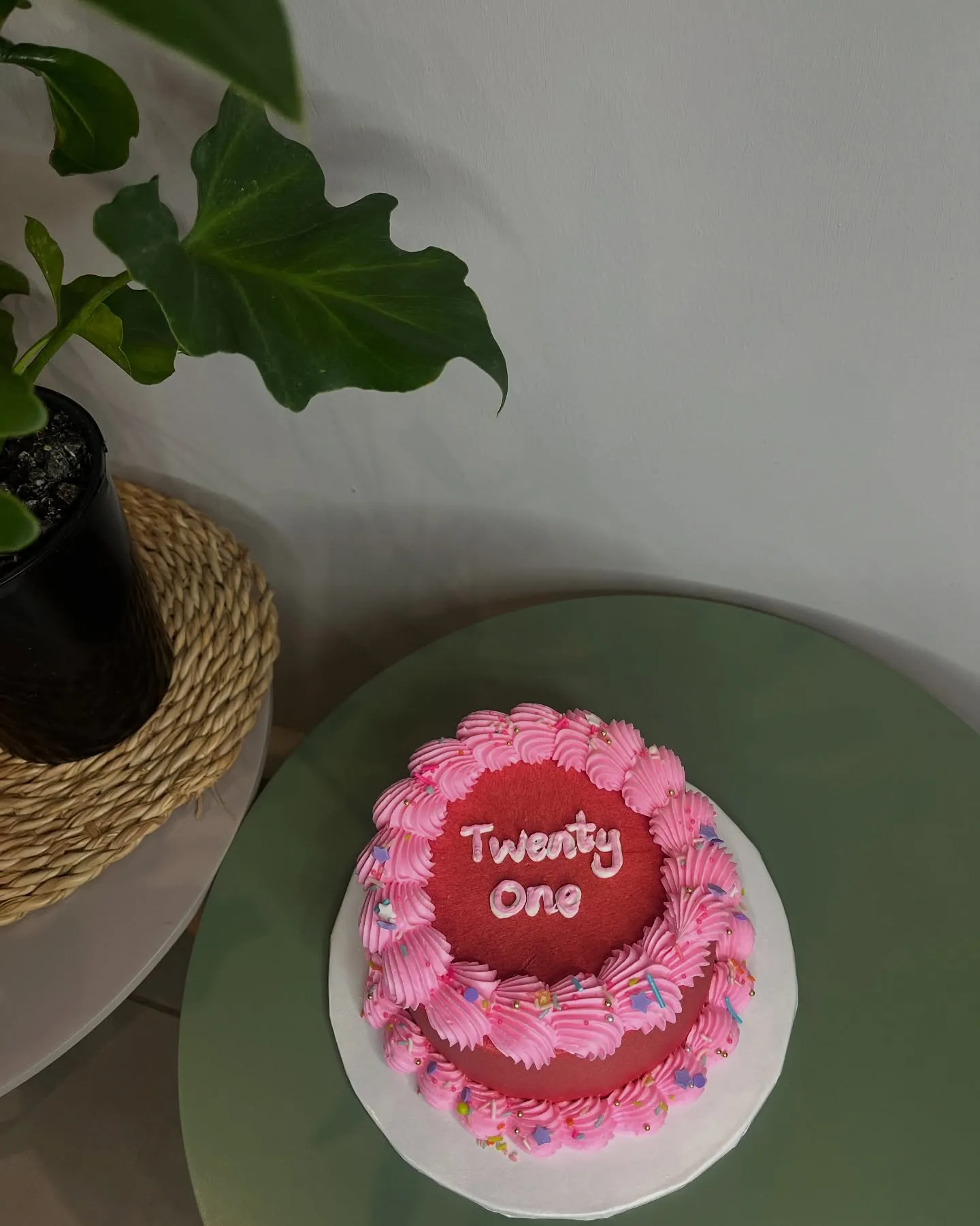 Small red cake with pink shells and 'Twenty One' on a sage plate